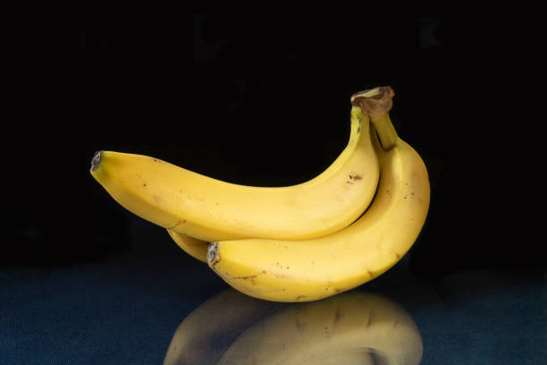 istock Ripe bananas to rest upon table with reflection 1292763136