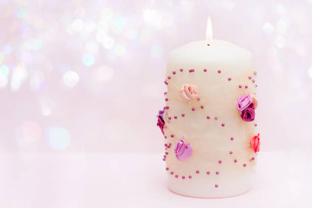 Stock photo shows a warm and festive Christmas scene featuring a glowing glass candle surrounded by decorative ribbons, bows, and seasonal ornaments. Soft lighting enhances the cozy, elegant holiday atmosphere, perfect for capturing Christmas celebrations, home décor inspiration, festive lifestyle photography