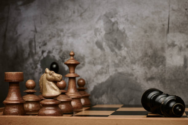 istock Chess pieces on a wooden chessboard defeat the black king 1292766030