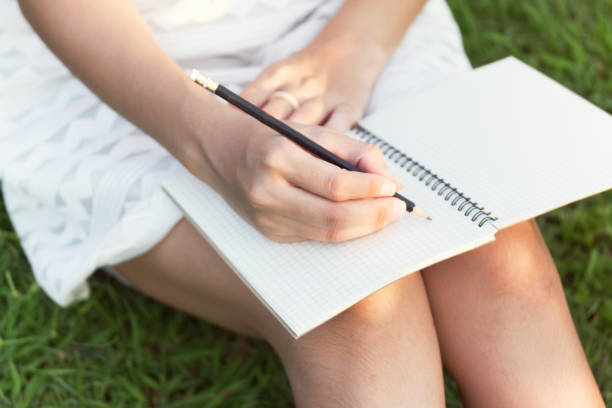 istock girl with pen writing on notebook on grass outside 1292766133