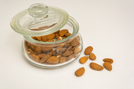 Closeup image of jar full of Almonds with white background with space for text