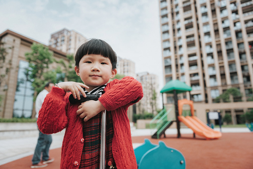 portrait of little chinese girl with scooter at playground in modern residential district