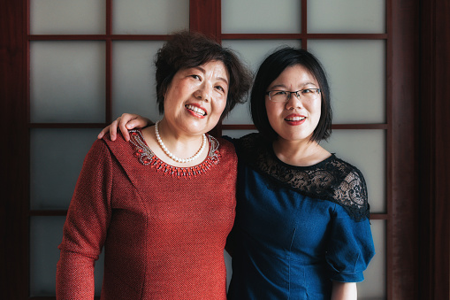 portrait of chinese adult woman embraced with her mother in living room