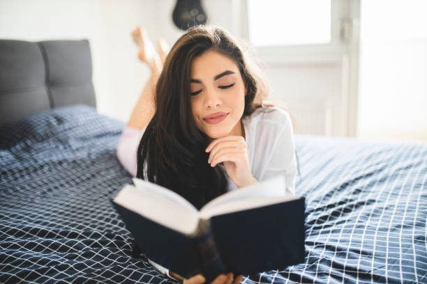 istock Woman reading book and lying on bed while resting at home 1292771013