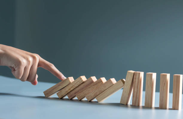istock businessman hand taking Falling wooden Dominoes effect from continuous toppled or risk, strategy and successful intervention concept for busine 1292771198