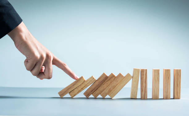 istock businessman hand taking Falling wooden Dominoes effect from continuous toppled or risk, strategy and successful intervention concept for business. 1292771204
