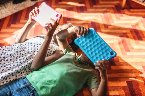 little girl and her brother looking at digital tablet at carpet - african ethnicity brother ethnic little boys imagens e fotografias de stock