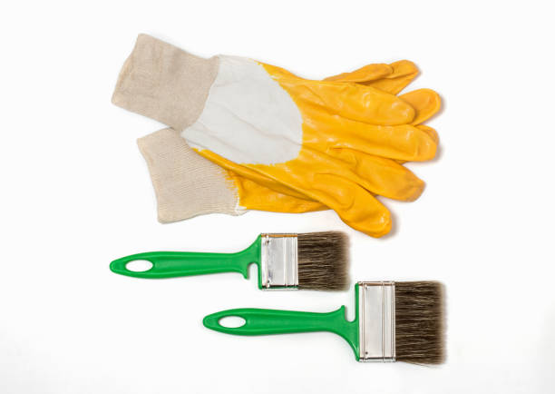 construction protective gloves in yellow with two green brushes on a white background.