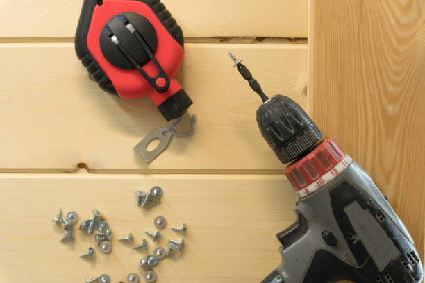 istock Cordless drill and screws. Electric drill with drill bits, screws on wooden background. Bunch of screws on wood planks. Assorted tools. Handyman professional DIY project workplace tabletop. 1292771655