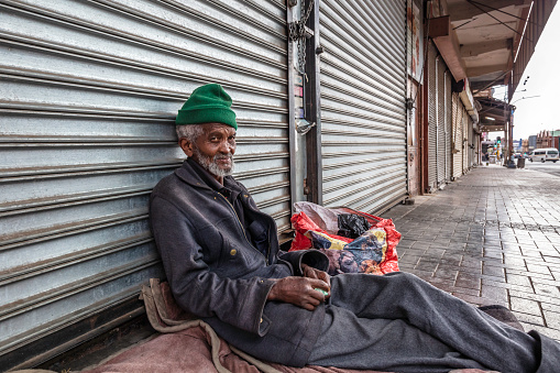 African senior man homeless and sleeping in the sidewalk streets of Johannesburg city centre, unhappy and hopeless.