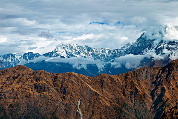 istock Snow covered mountain peak Chaukamba in clouds - the Himalayas, India 1292773435