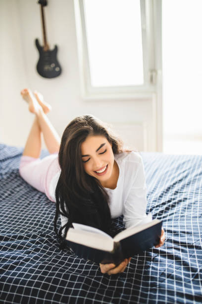 istock Woman reading book and lying on bed while resting at home 1292773677