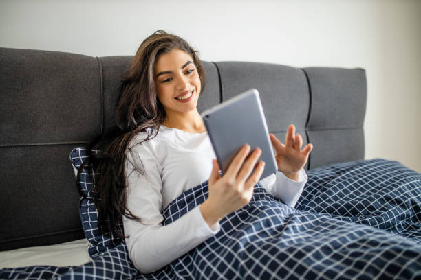 istock Young woman using digital tablet while lying on bed at home 1292774673