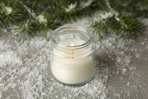 istock Scented candle, pine branches and snow on gray background 1292775760