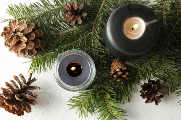 istock Scented candles and pine branches with cones on white table 1292775774