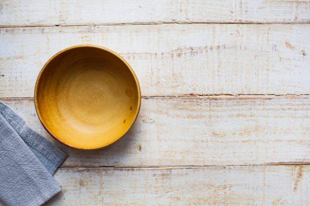 istock Empty yellow bowl, with a grey napkin, on a rough wooden surface viewed directly above with copy space 1292775887