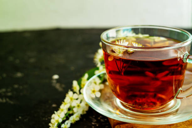 istock A cup of flower tea with spring cherry blossom on a black background. Copy space 1292776799