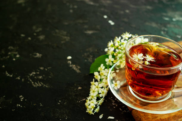 istock A cup of flower tea with spring cherry blossom on a black background. Copy space 1292776804
