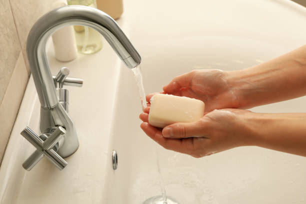 istock Woman washing hands in bathroom sink with soap 1292776873