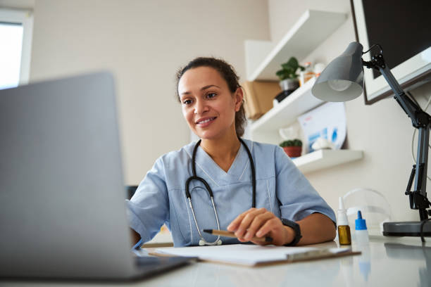 doctor clicking on a laptop before her - doutor imagens e fotografias de stock