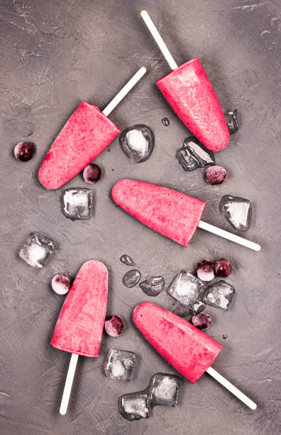 istock frozen red ice cream on a stick with chunks of ice on a black background. 1292778333