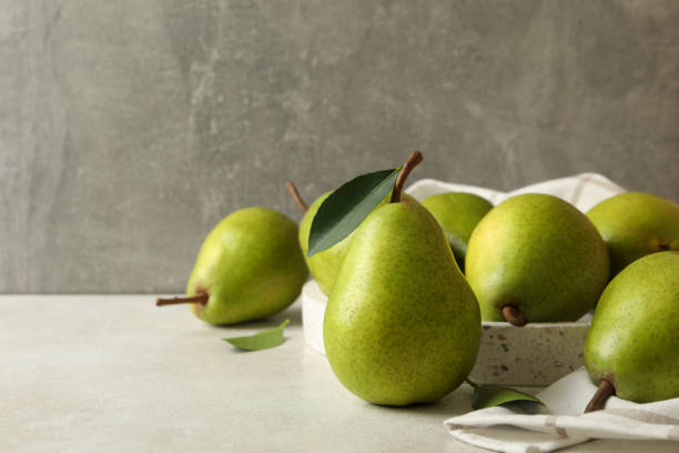 istock Tray with green pears and kitchen towel on white textured background 1292778661