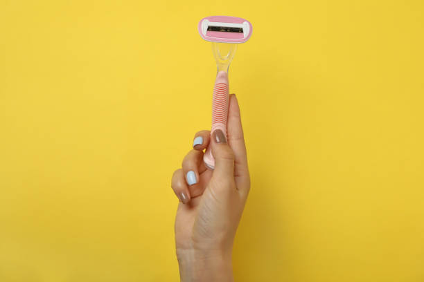 istock Female hand hold razor on yellow background, space for text 1292779518