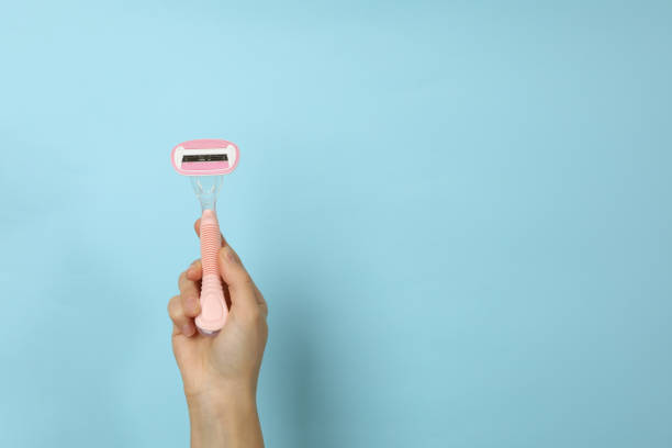 istock Female hand hold razor on blue background, space for text 1292779619