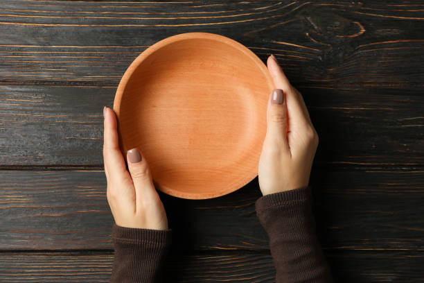 istock Female hands holding bowl on wooden background 1292781837