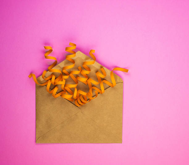 istock Beautiful craft envelope with yellow confetti on a pink background 1292784122