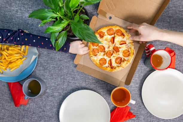 istock Small pizza pepperrone in a box on a set table, top view, family lunch. 1292784315