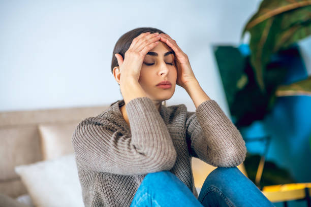 istock Dark-haired woman sitting on bed and looking frustrated 1292786661