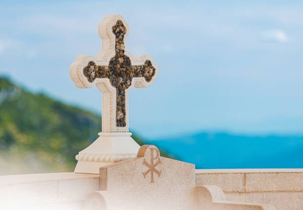 cruze no mosteiro ostrog da igreja ortodoxa sérvia contra céu azul e montanha. viagem de montenegro, europa. - ostrog - fotografias e filmes do acervo