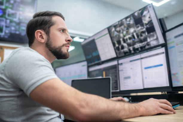 Young adult man watching computer screens