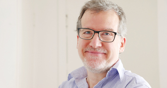 Mature man in blue shirt portrait with a neutral expression