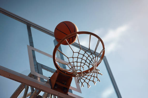 Shoot for the sky and you will score Closeup shot of a basketball landing into a net on a sports court basketball ball photos stock pictures, royalty-free photos & images