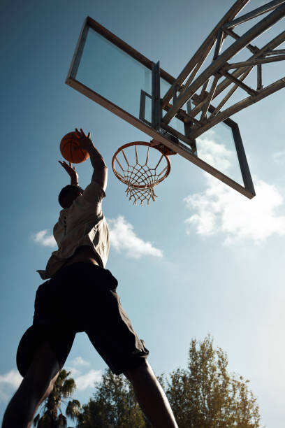 Flyin' and slammin' Shot of a sporty young man playing basketball on a sports court silhouette of basketball player slam dunk stock pictures, royalty-free photos & images