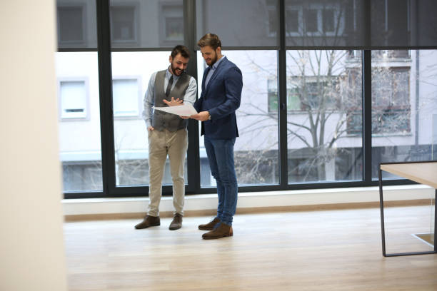 istock Two young experts are looking on printed charts, standing and talking. 1292792933