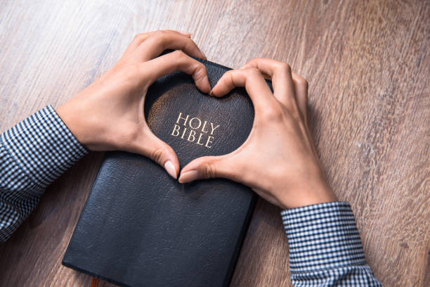 istock Holy bible with heart shape hands 1292793781
