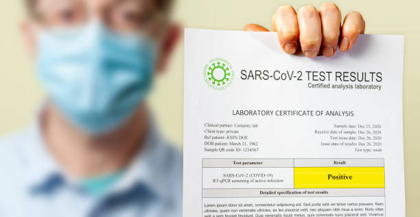 istock A positive test result document for SARS-CoV-2 coronavirus causing COVID-19 held up by man wearing a protective surgical face mask 1292793939