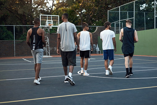 Rearview shot of a group of sporty young men hanging out on a basketball court