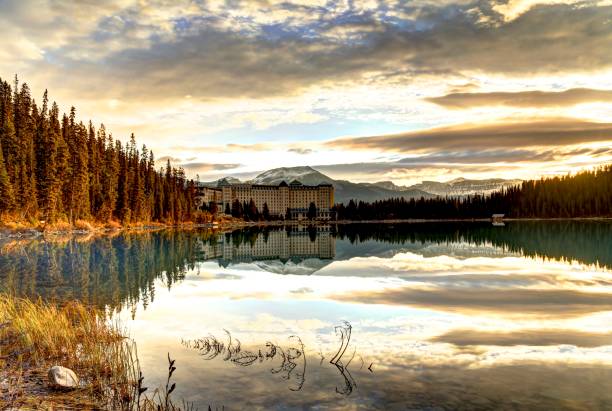 il maestoso lake louise hotel nel banff national park visto dall'altra parte dell'acqua all'alba in autunno. - lake louise national park landscape forest foto e immagini stock