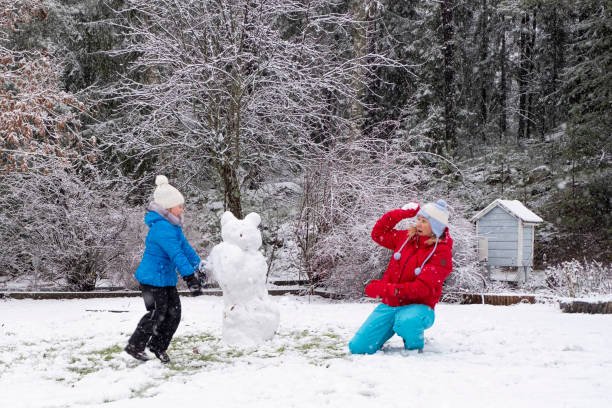 kaukasische mädchen mit einem kind, ein mädchen von 5 jahren, spielen und werfen schneebälle. winter fröhliches wochenende mit der familie. - child winter snow 4 5 years stock-fotos und bilder