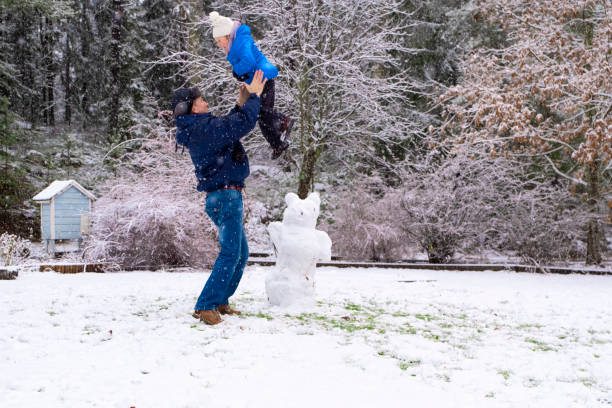 un hombre caucásico sostiene a una niña de 5 años en sus brazos y la levanta. invierno alegre fin de semana con la familia. - pareja acogido al aire libre fotografías e imágenes de stock