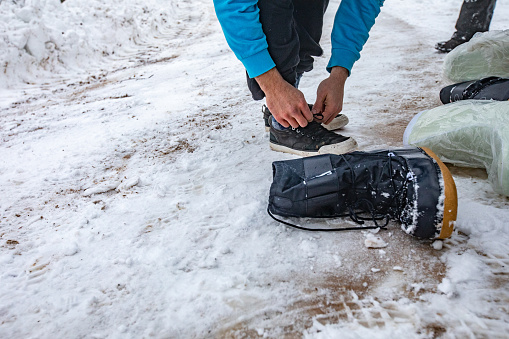 Young Man Changing Shoes To Snow Boots.