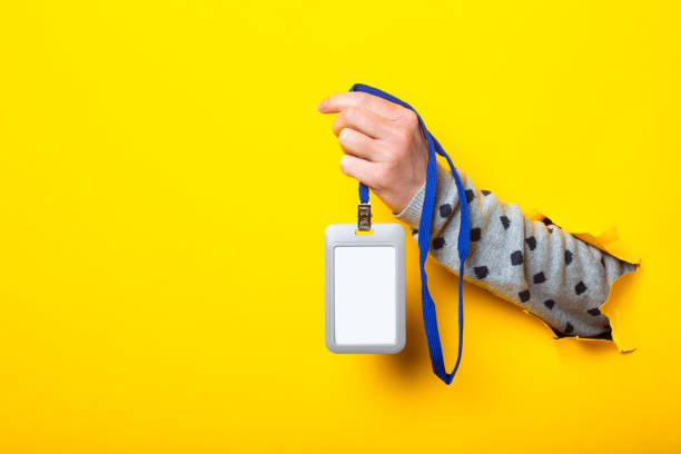 istock Woman's hand holds a blank name tag on a torn yellow background 1292795116
