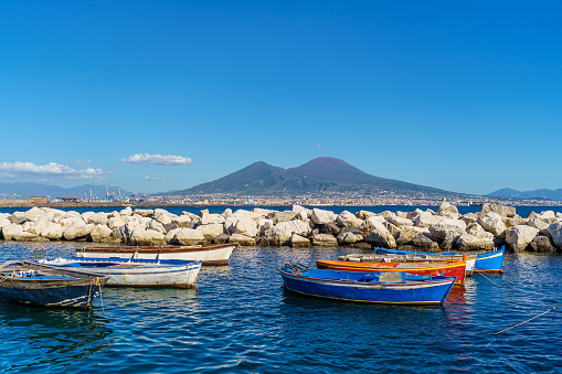 View of Volcano Vesuvius view from seafront with colorful boats in the foreground, Naples, Campania, Italy.