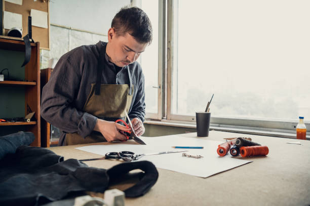 istock A young shoemaker makes a drawing for a pattern for leather shoes on a table in his workshop 1292802172