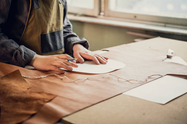 istock A young guy in a leather workshop transfers a pattern from paper to leather 1292802186
