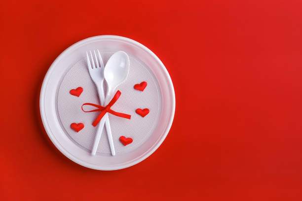 istock Top view of plastic white disposable fork and spoon tied with red ribbon 1292808060